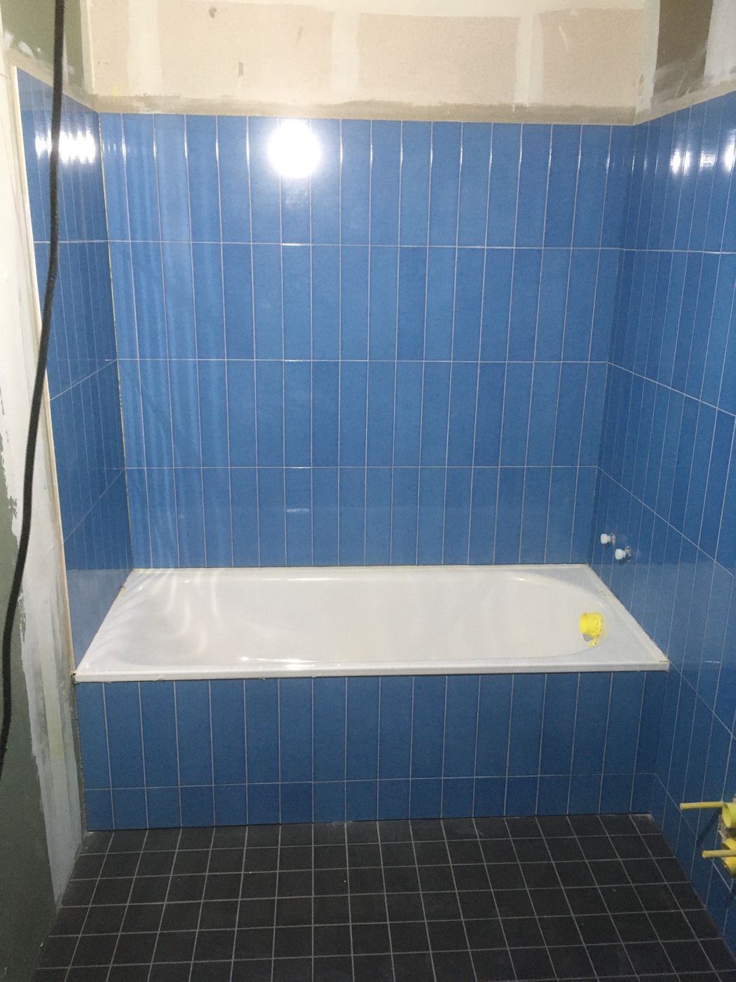 Badezimmer mit blauen Wandplatten und Badewanne