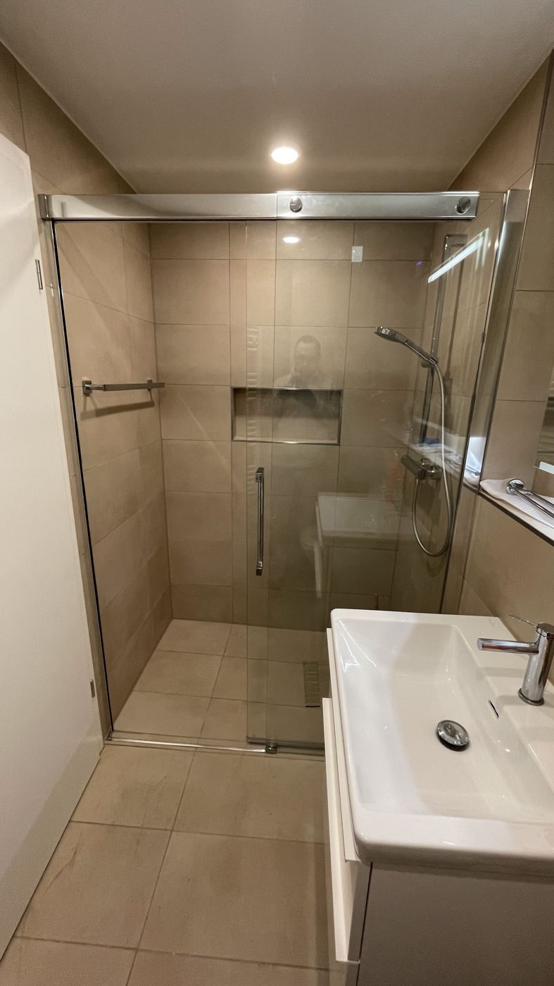 Dusche mit Schiebetür und Wandnische, daneben ein Waschtisch