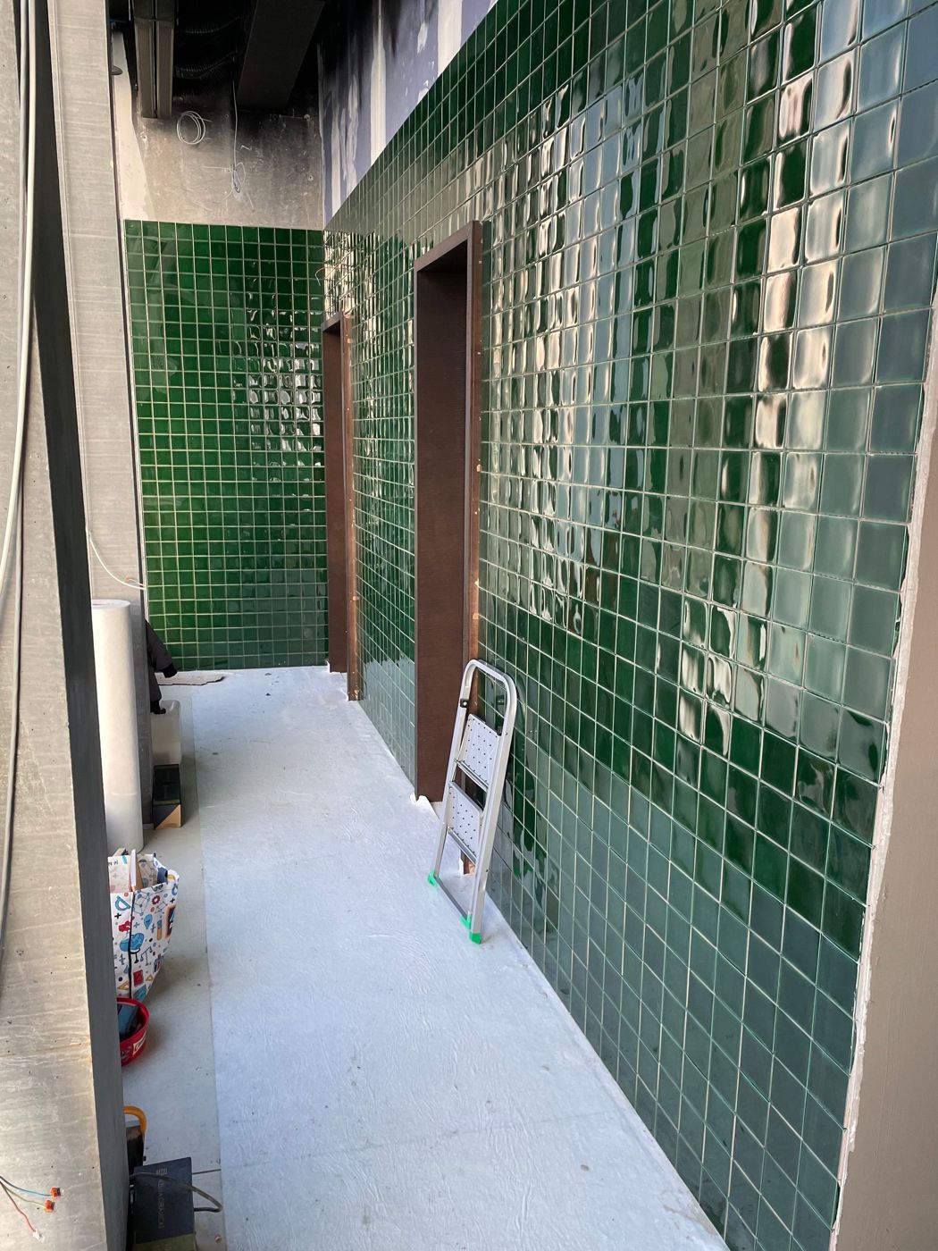 Gang mit grün glasierten Wandplatten im Rohbau